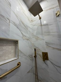 Marble shower wall with a niche and gold fixtures