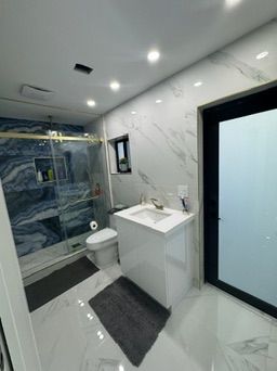 Bathroom with a blue marble shower wall and a white vanity