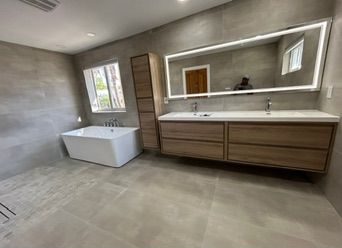 Double wood vanity with a lit mirror and a freestanding tub