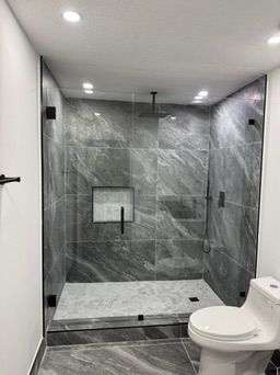 Gray stone shower with black fixtures and a glass door
