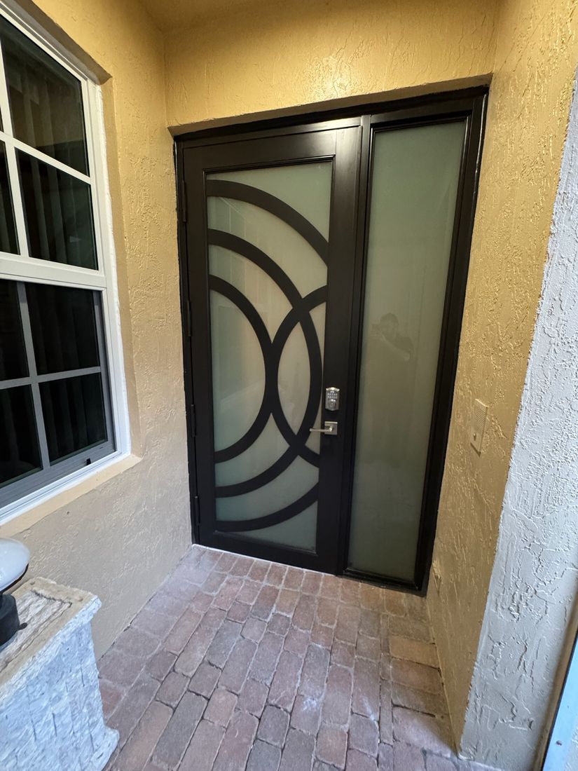 Dark entry door with a curved iron design and a sidelight