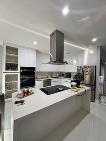 Kitchen with a white quartz island, black cooktop and range hood