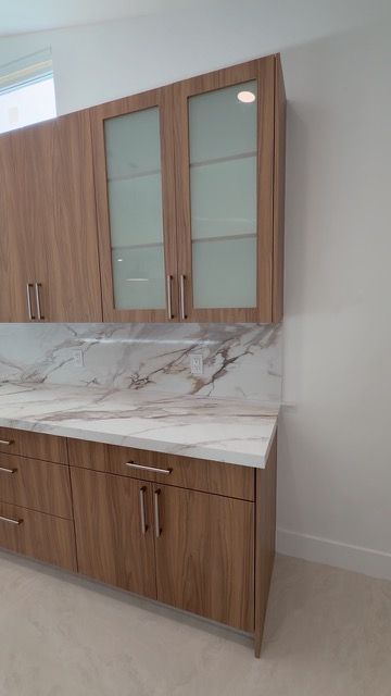 Wood cabinets with frosted glass doors and a marble backsplash
