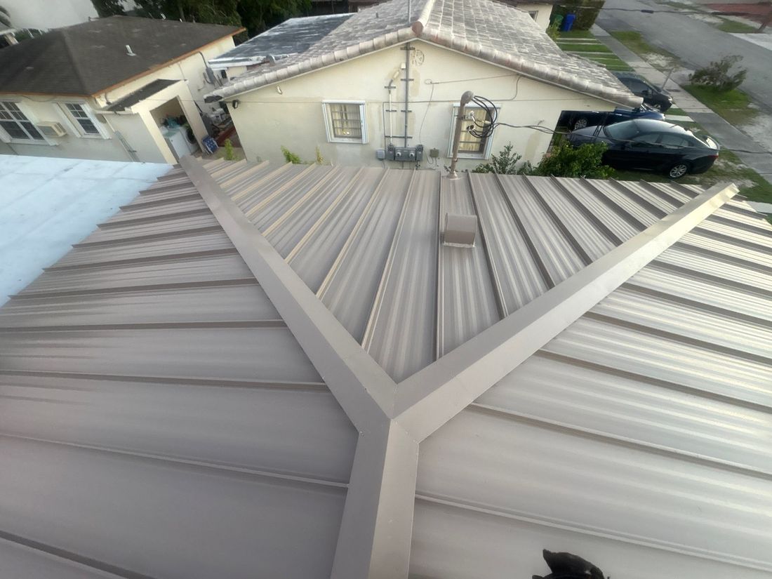 Standing seam metal roof in light gray with a hip ridge